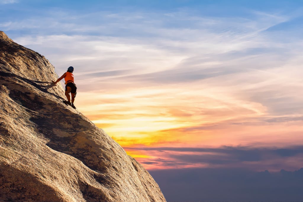 Climber conquers rock face at sunset, embracing the thrill and challenge.